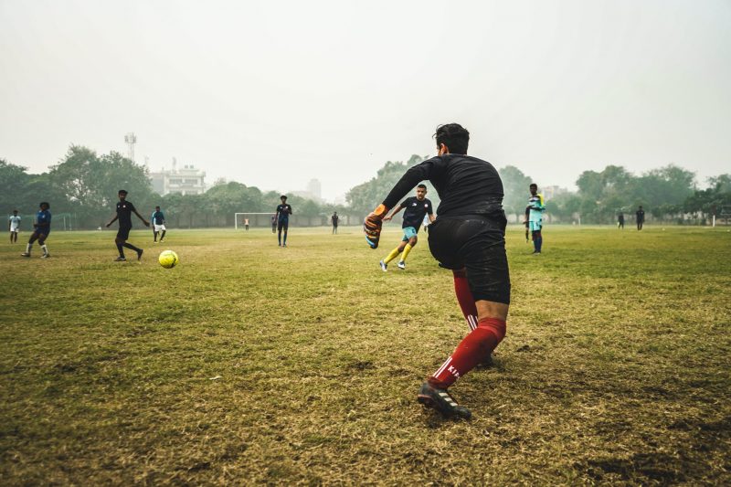 people playing soccer on grass field during day